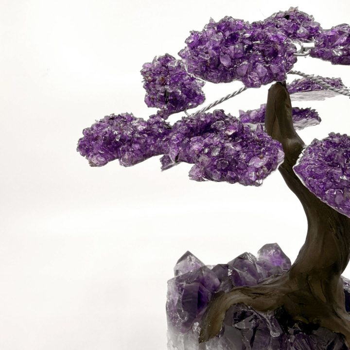 Side detail of amethyst gemstone tree showing crystal branches and sculpted trunk