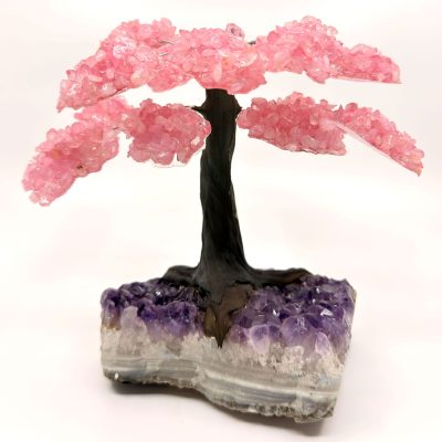 Rose quartz gemstone tree sculpture with pink crystal branches displayed on a natural amethyst base