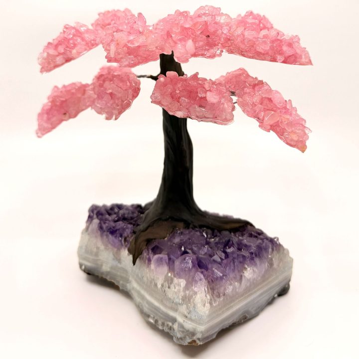 Rose quartz gemstone tree sculpture with pink crystal branches displayed on natural amethyst base