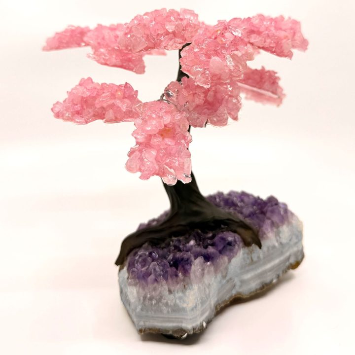 Rose quartz gemstone tree on amethyst base shown at an angle, highlighting natural crystal texture