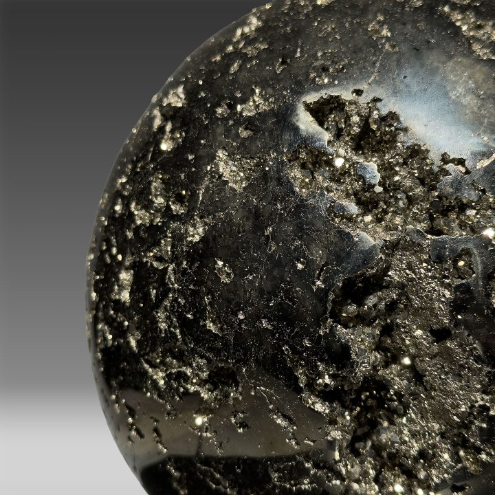 Macro shot of Pyrite sphere with reflective golden crystal inclusions.