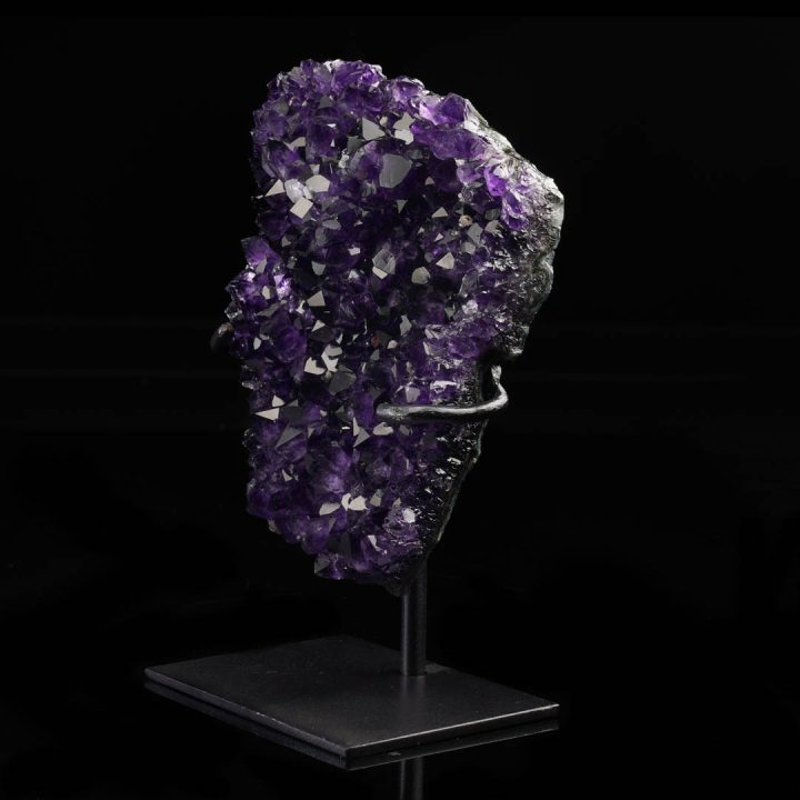Natural amethyst quartz geode specimen with crystalline structure on metal stand