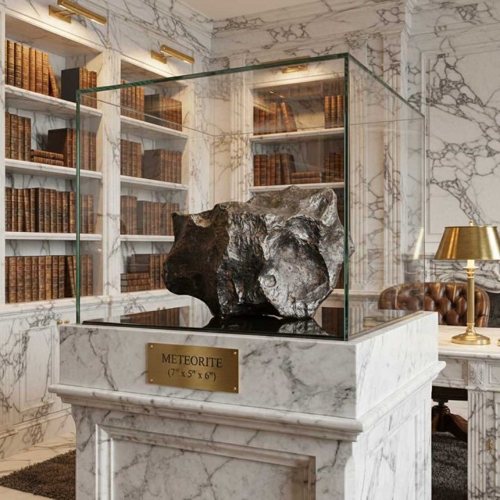 Campo del Cielo 18 lb iron meteorite displayed on a marble pedestal in a classic library setting, showcasing natural iron texture