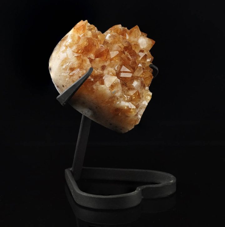 Natural citrine crystal heart displayed against black background