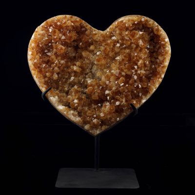Large hand-carved golden citrine heart crystal displayed on a stand