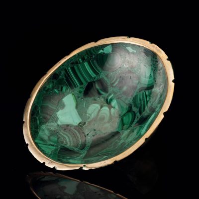 Malachite bowl with natural green banding and gold edge on black background