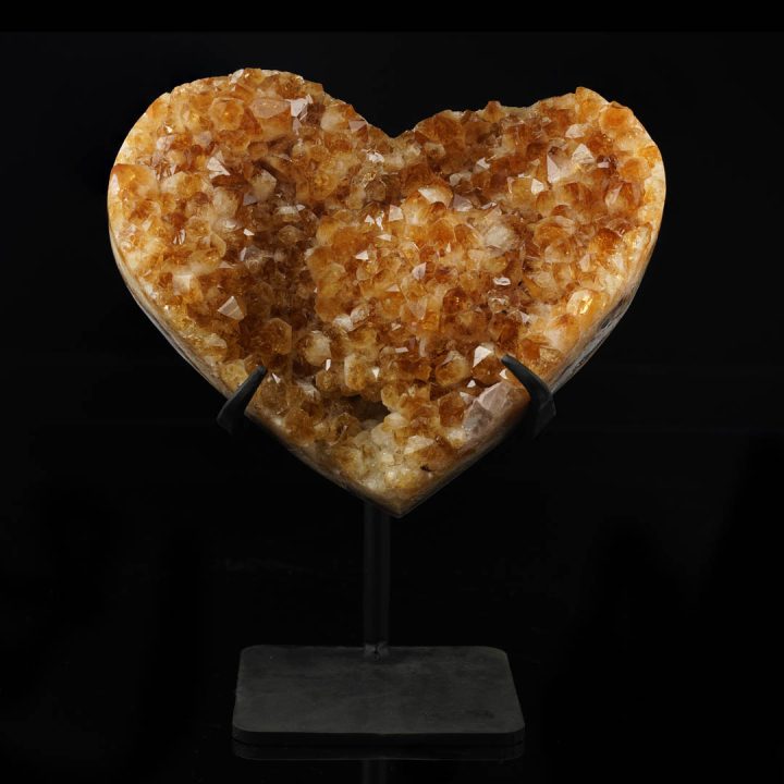 Medium hand-carved citrine heart crystal displayed on a stand