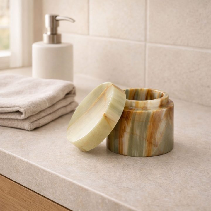 Round onyx stone box with lid displayed on a bathroom counter, showcasing natural banded patterns and polished finish