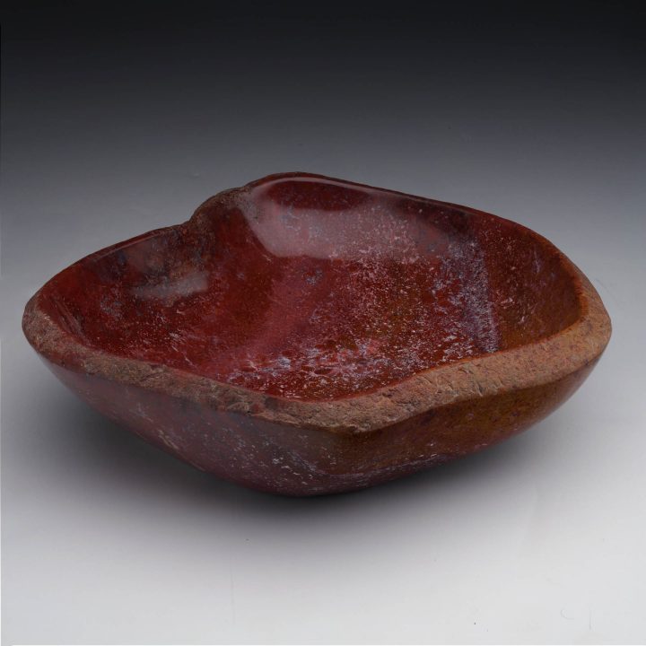Fossilized red petrified wood bowl presented in full view, showing natural grain and sculptural form