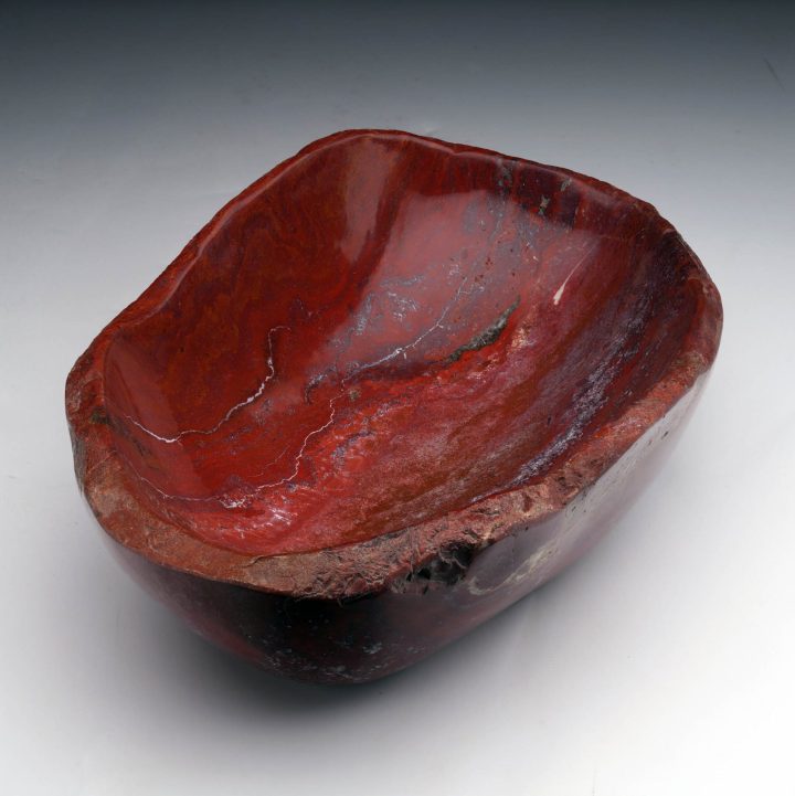 Natural red petrified wood bowl presented in full view, displaying fossilized wood patterns and smooth finish
