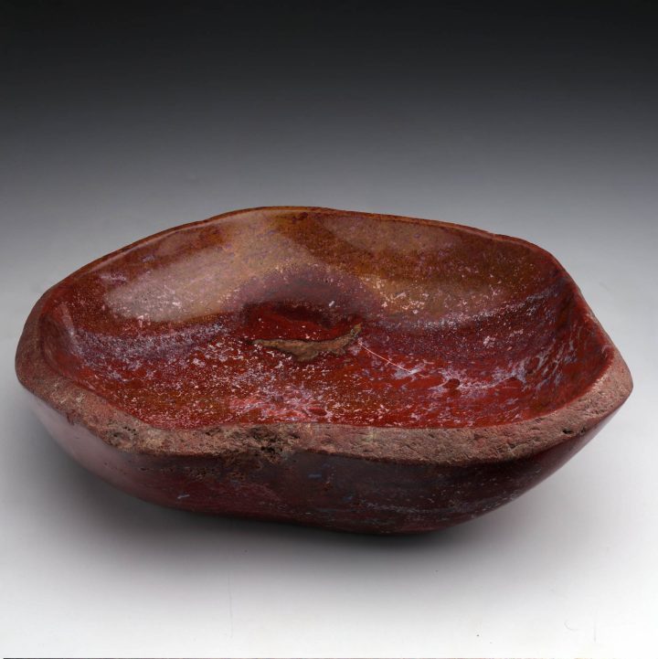 Red petrified wood bowl with organic shape, showcasing natural fossil wood grain and polished interior