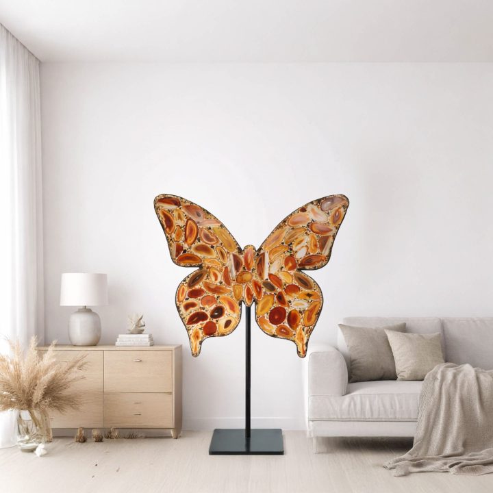 Agate slice butterfly sculpture displayed on a stand in a modern living room, showcasing natural banded stone patterns