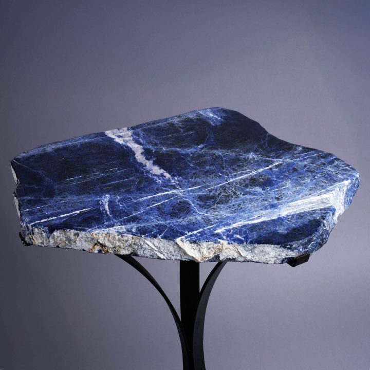 Natural blue stone side table shown at an angle, highlighting rich blue tones and irregular slab shape