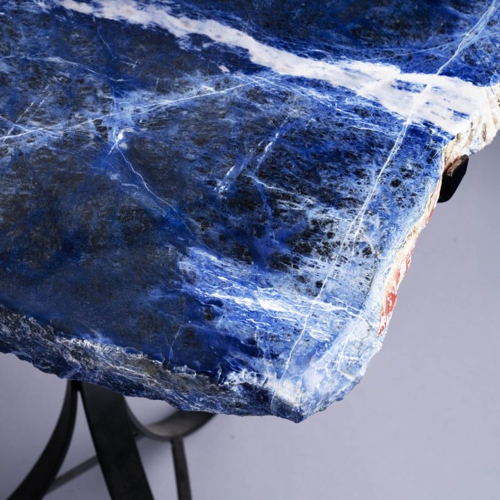 Blue stone slab side table with organic edge and black metal base displayed in studio setting
