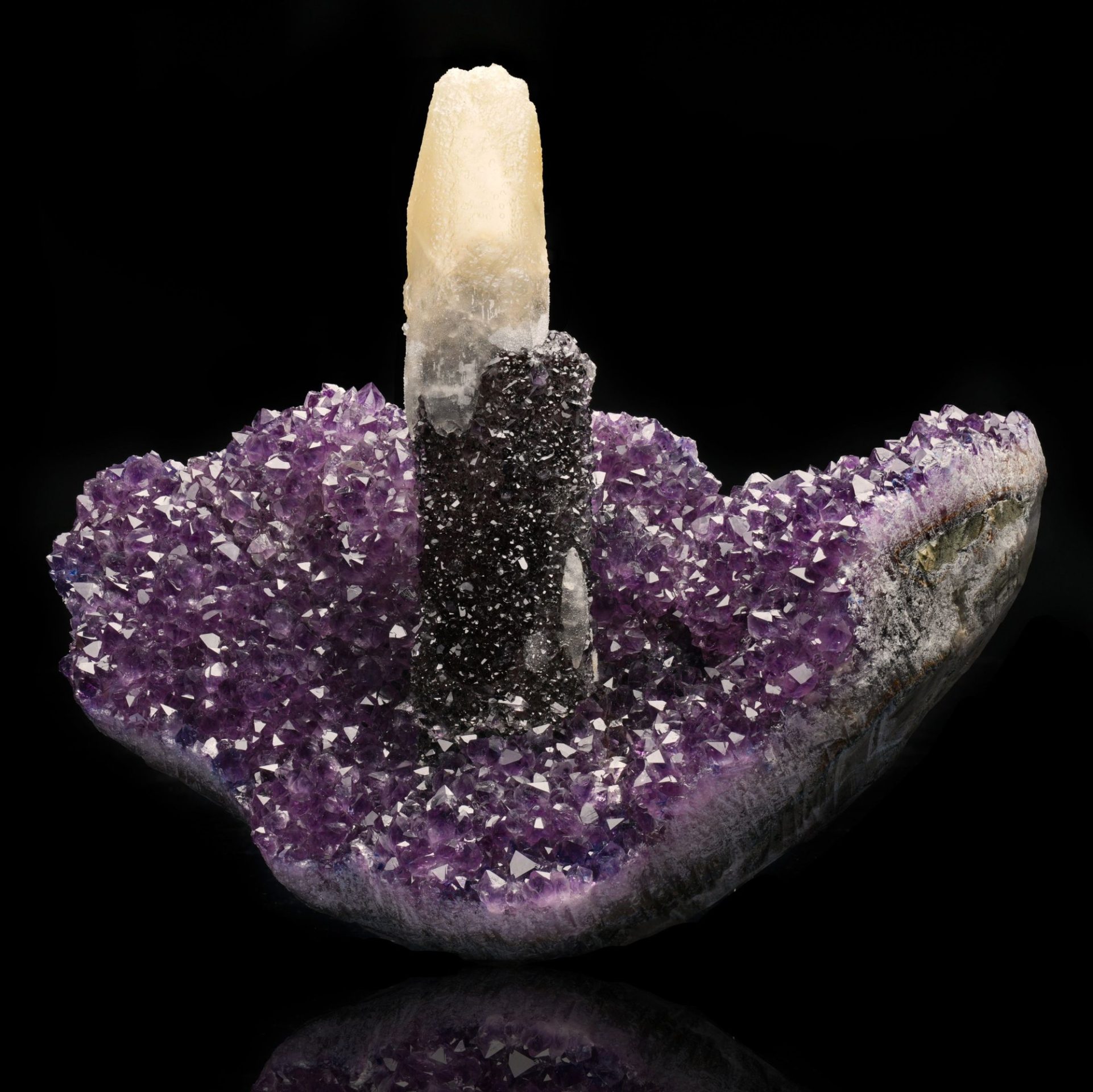 A stunning amethyst geode with a tall, light-colored stalactite growing from its purple crystal interior.
