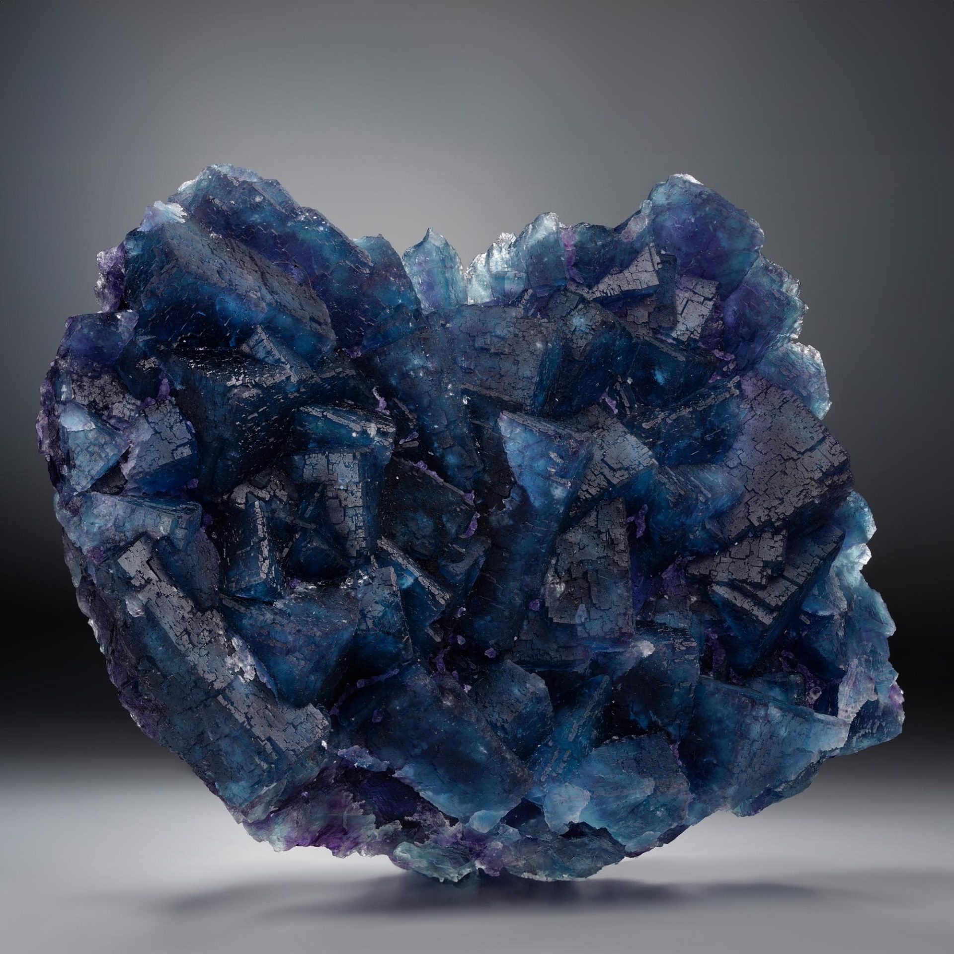 A large, dark blue and purple fluorite crystal cluster with complex, textured surfaces.