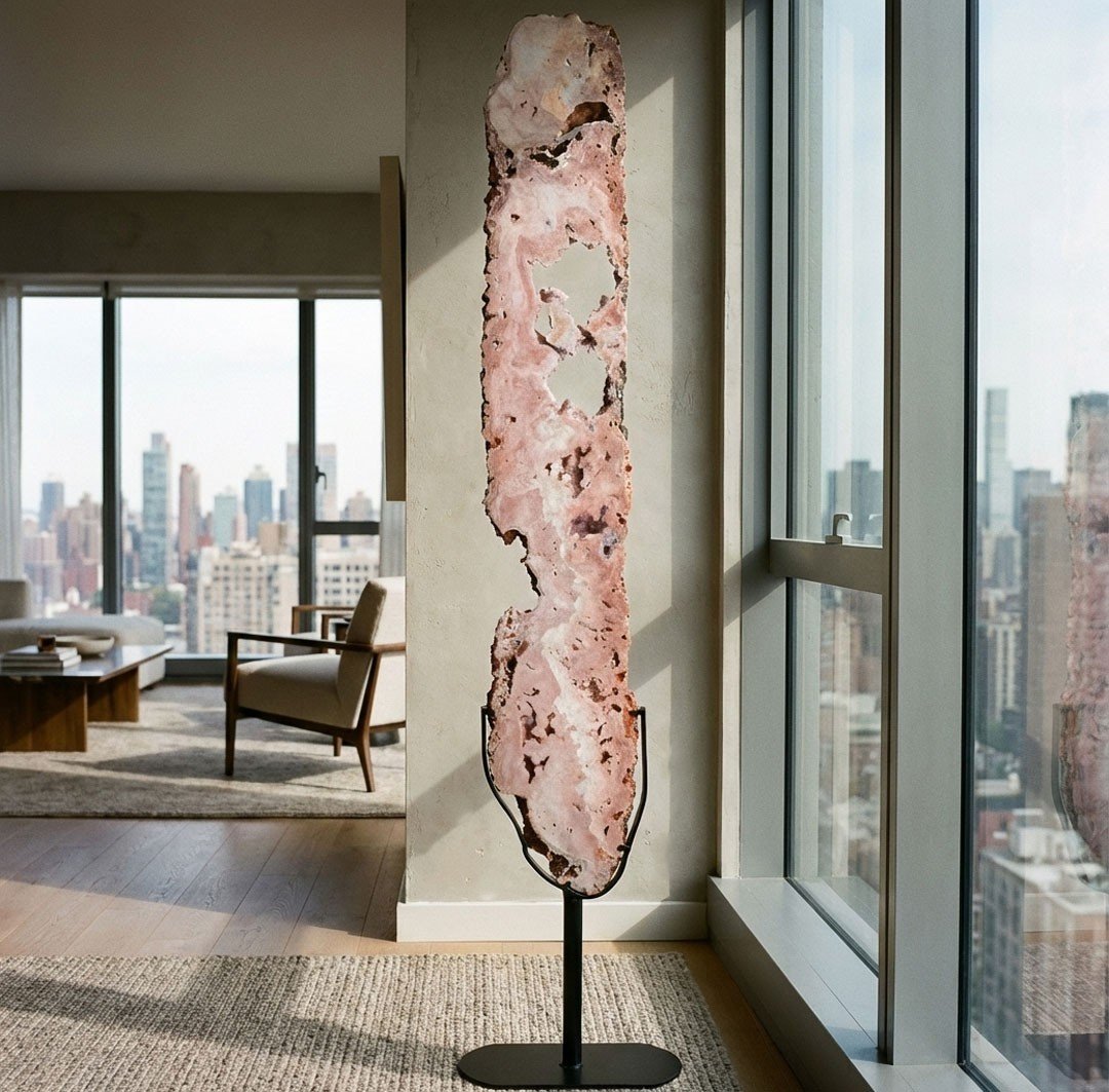A large, natural pink crystal slab stands as unique decor in a luxurious living room with a city view.