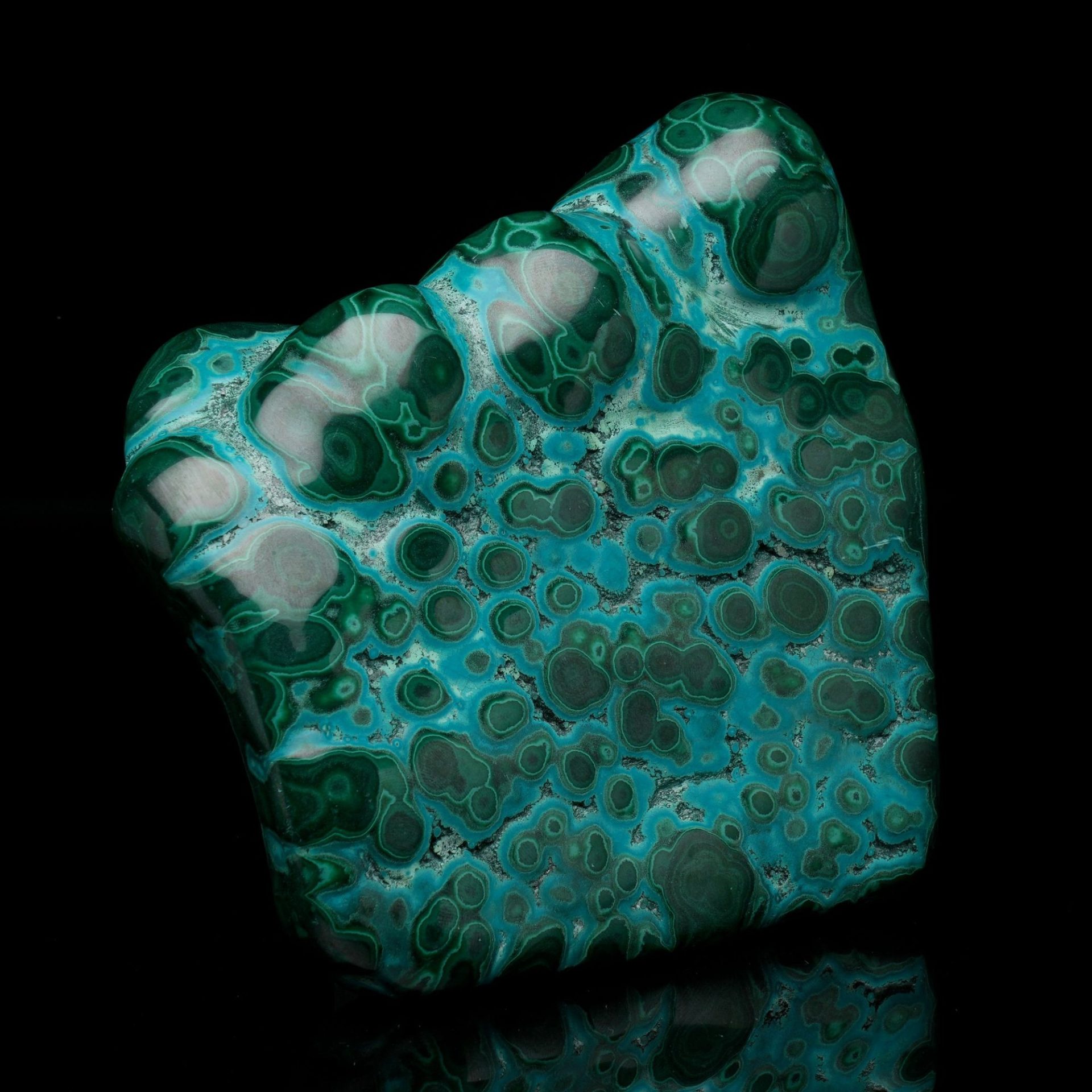 A polished mineral specimen displaying vibrant teal and dark green swirling patterns against a black background.