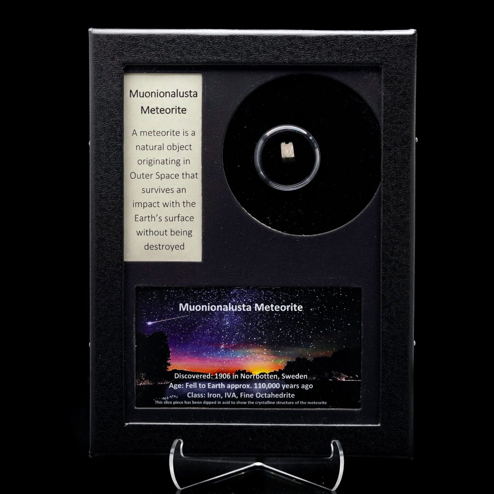 A framed display case featuring a small Muonionalusta meteorite slice, descriptive text, and a starry sky image.